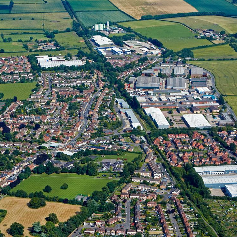 Aerial view of Thame, Oxfordshire, showing residential areas, commercial buildings and surrounding countryside.